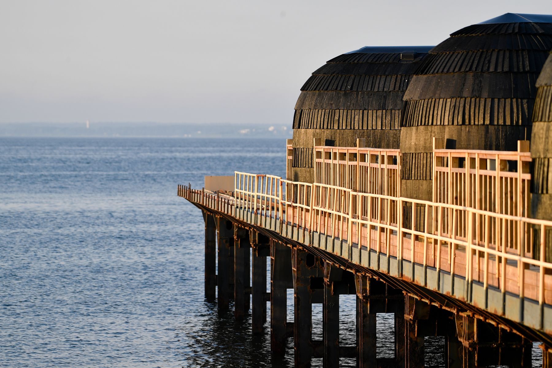 Barrel saunas on a wooden pier over the sea at sunset